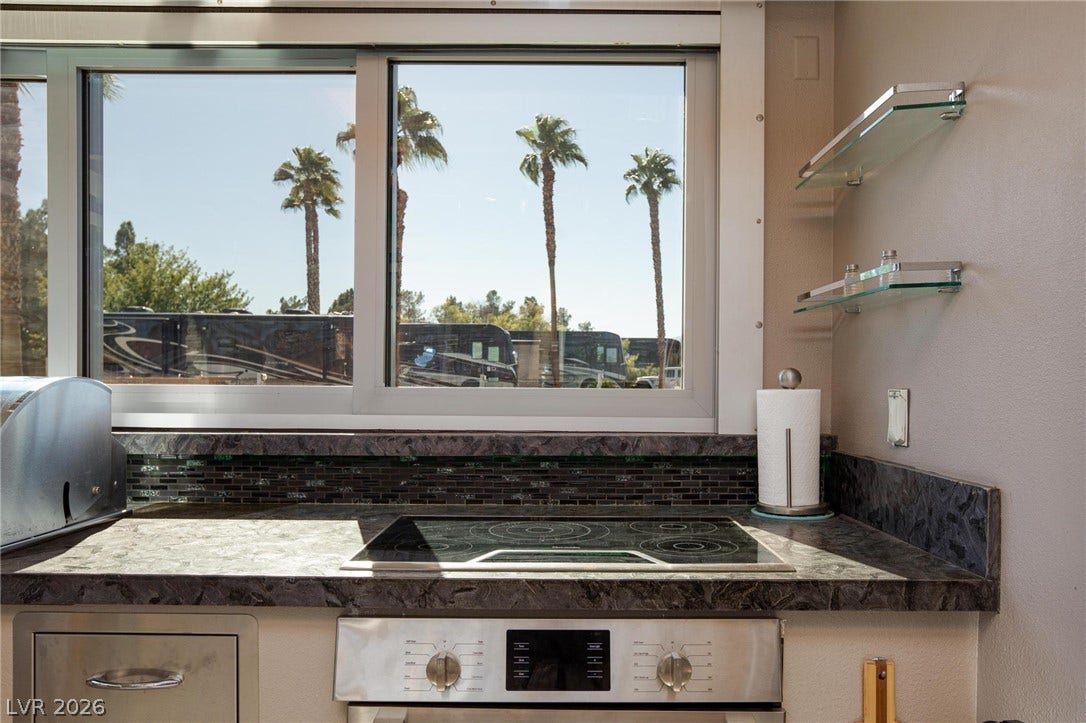 8175 Arville Street, #142, Las Vegas, NV 89139 A modern cooktop and sleek stone countertop sit beneath windows framing views of palm trees.