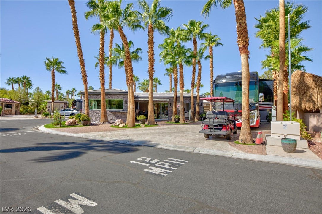 8175 Arville Street, #142, Las Vegas, NV 89139 Mature palms frame this modern single-story exterior featuring stone accents and a paved drive.
