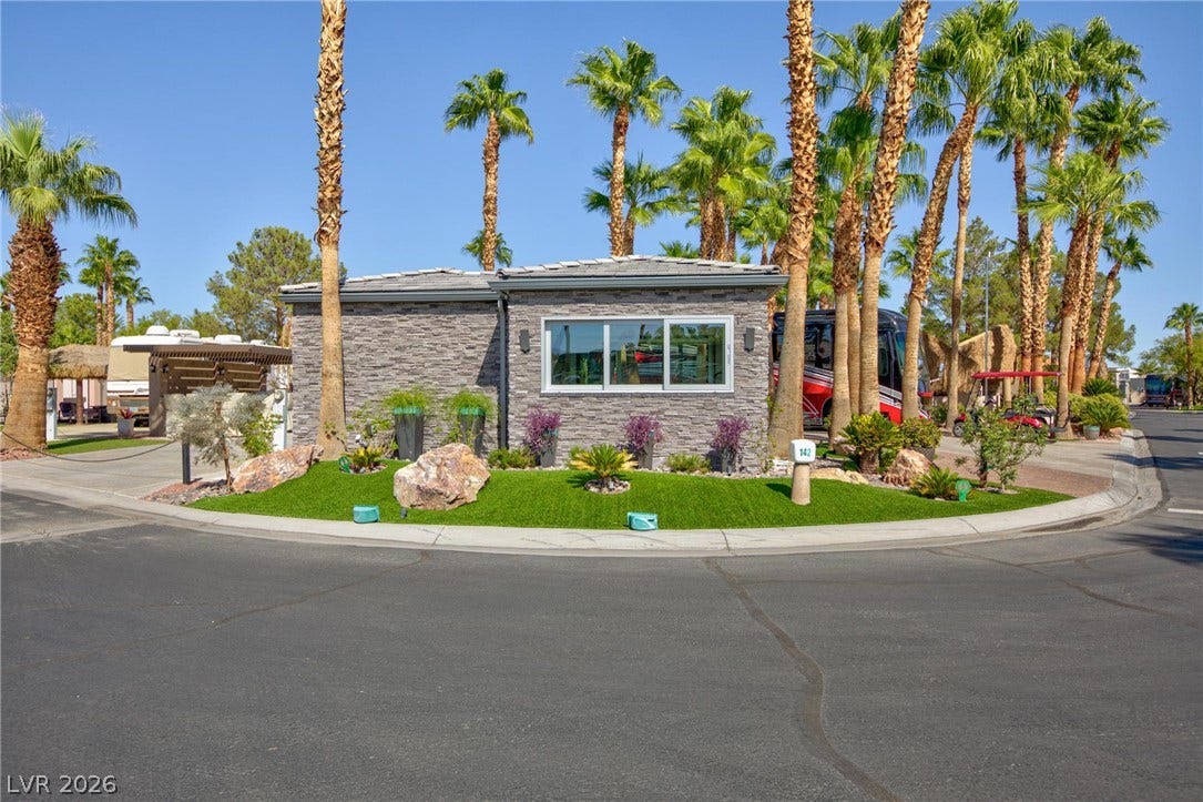 8175 Arville Street, #142, Las Vegas, NV 89139 Towering palm trees frame a modern stone exterior nestled along a manicured corner lot.