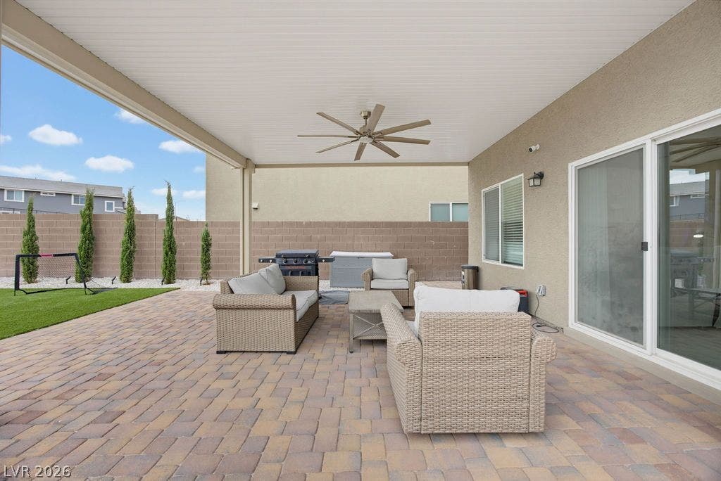 A spacious covered patio features clean brick pavers alongside a tidy lawn and privacy wall.