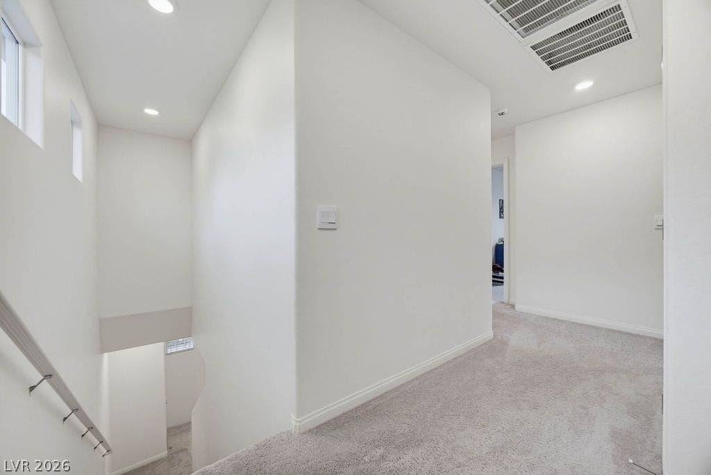 Recessed lighting and soft carpeting create a welcoming ambiance throughout this upper hallway.