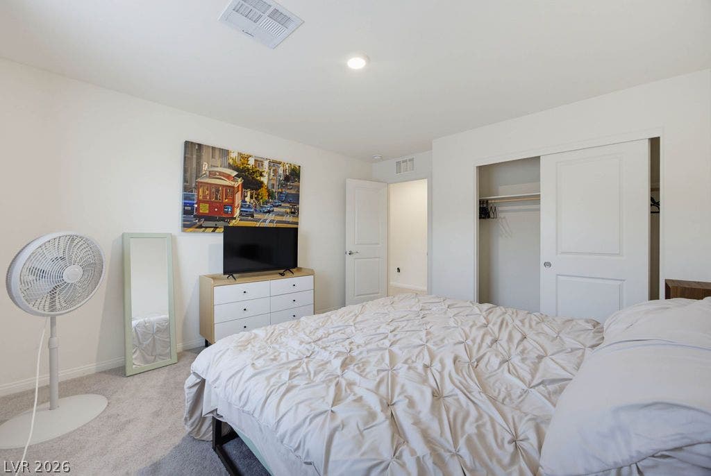 Soft carpet and clean white walls establish a serene, airy feel in this comfortable bedroom.