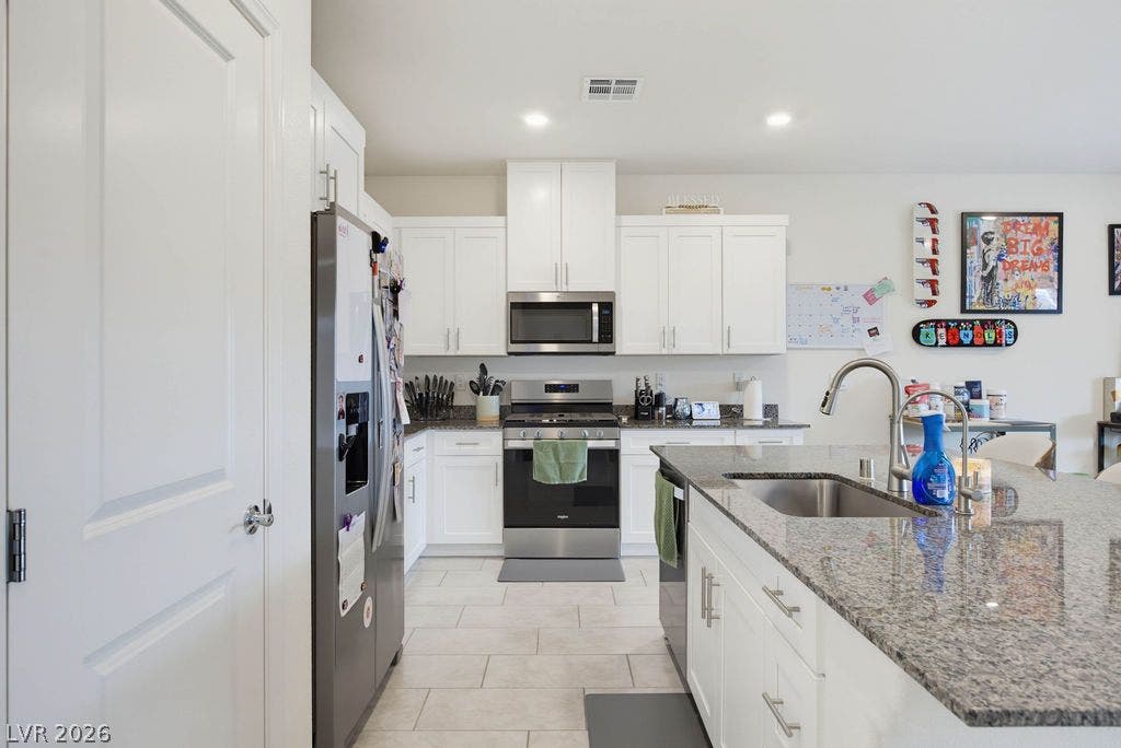 Polished stone countertops pair with white cabinetry and modern tile flooring in this functional kitchen.