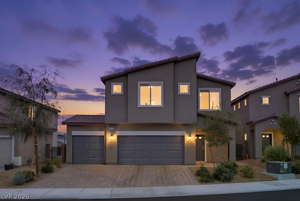 Bold geometric lines and a multi-car garage define this contemporary stucco exterior at twilight.