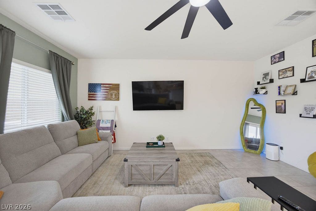 Natural light streams through large windows onto tile flooring in this welcoming living space.