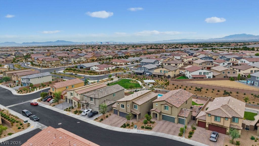 Distant mountains frame a sprawling neighborhood of modern houses lining curved paved streets.