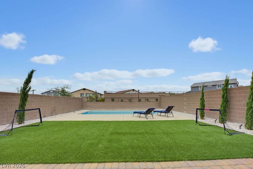 An inviting swimming pool lies beyond a manicured lawn enclosed by secure privacy fencing.