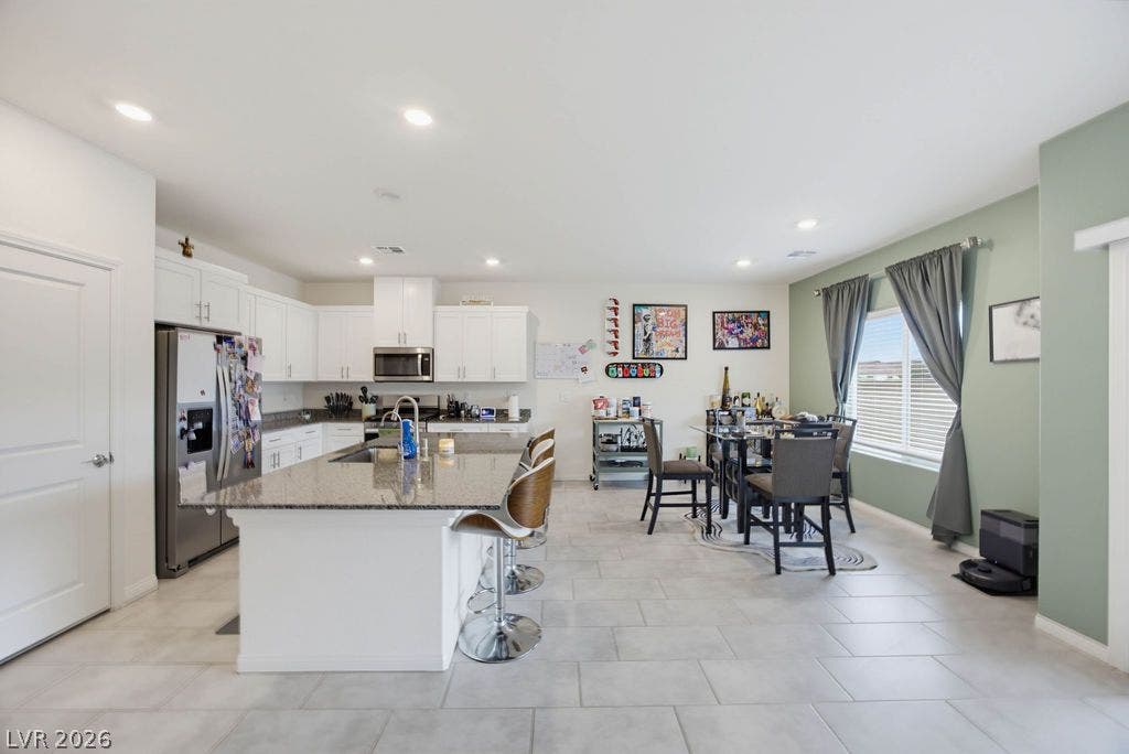 An open kitchen design transitions seamlessly into a dining area over sleek tile flooring.