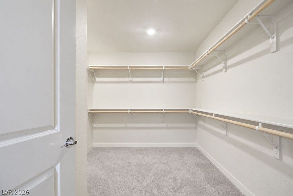 Ample built-in shelving and hanging rods maximize organization in this carpeted walk-in closet.