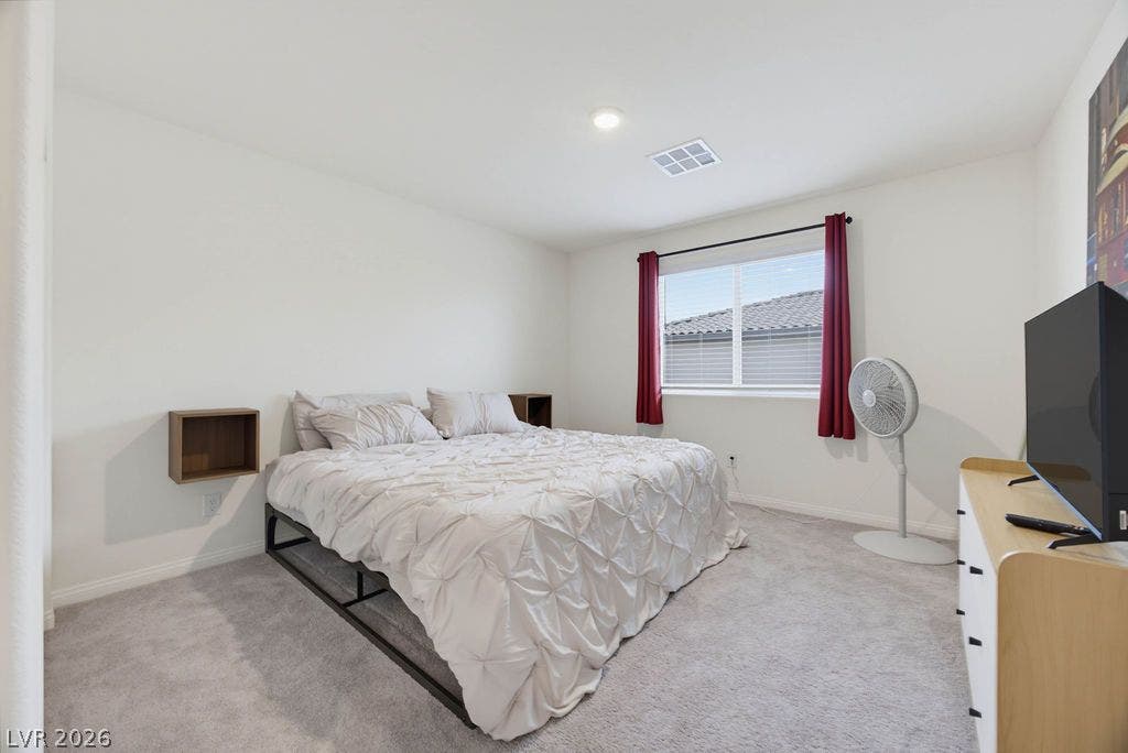 Plush carpeting anchors this peaceful bedroom under recessed lighting.