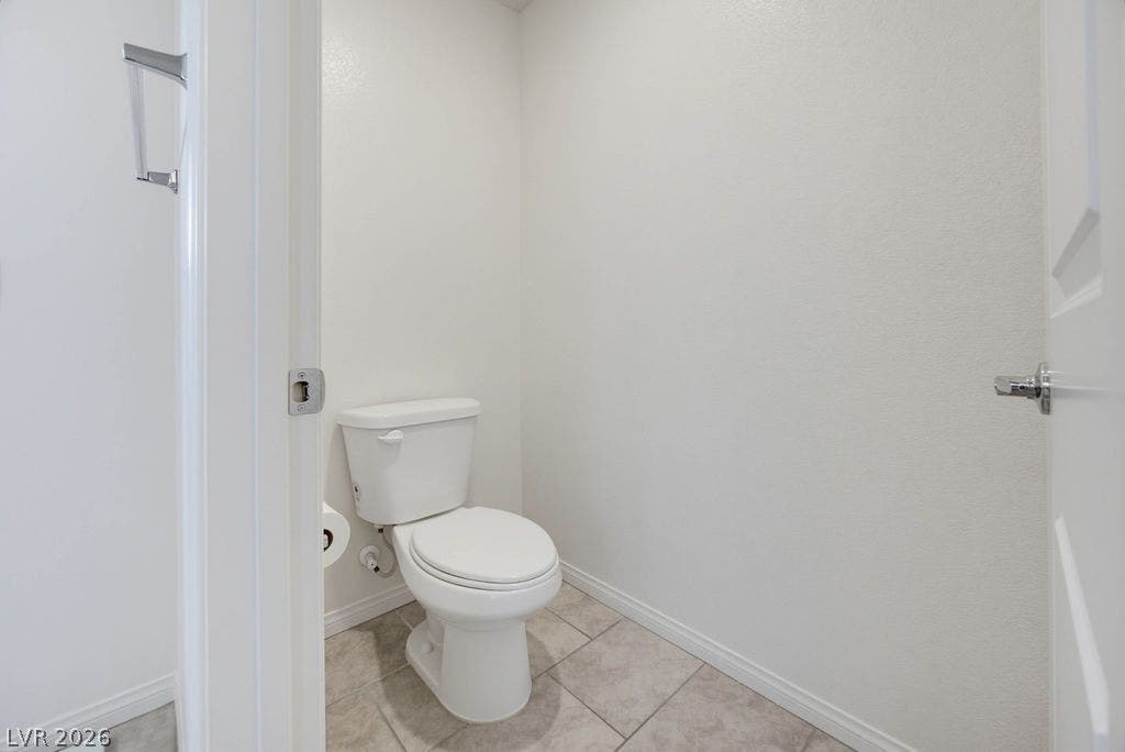 A private water closet features tile flooring and neutral walls.