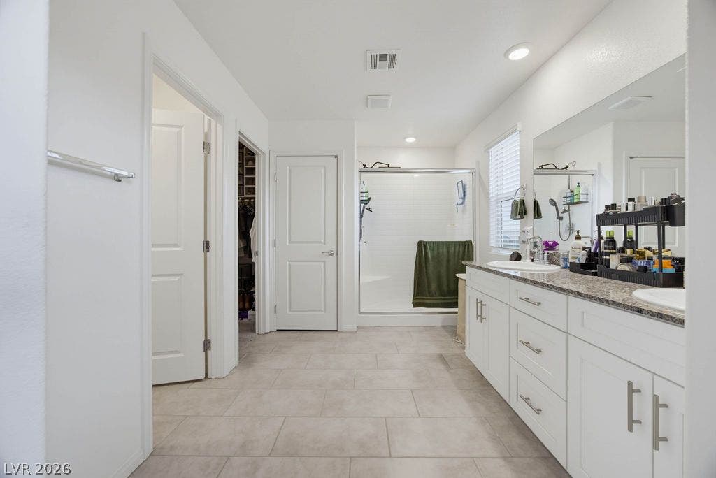 Clean tile flooring and stone counters enhance this well-appointed bathroom with a walk-in shower.