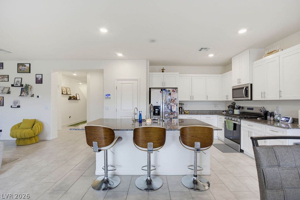 An open kitchen layout features clean cabinetry and a central island over tiled flooring.