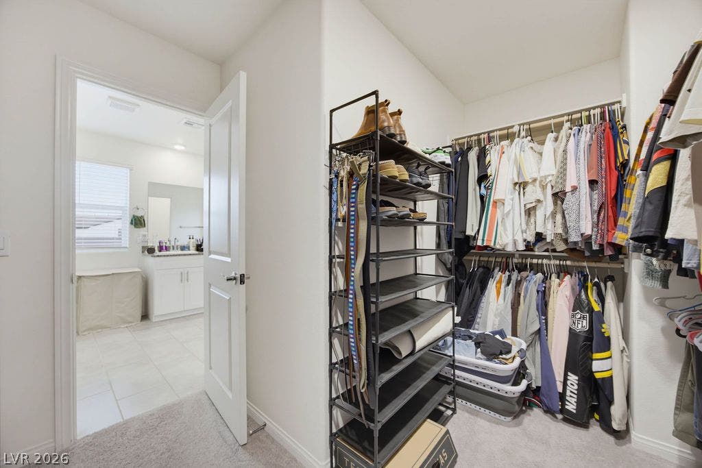 Ample hanging rods and shelving optimize storage within this carpeted walk-in closet.