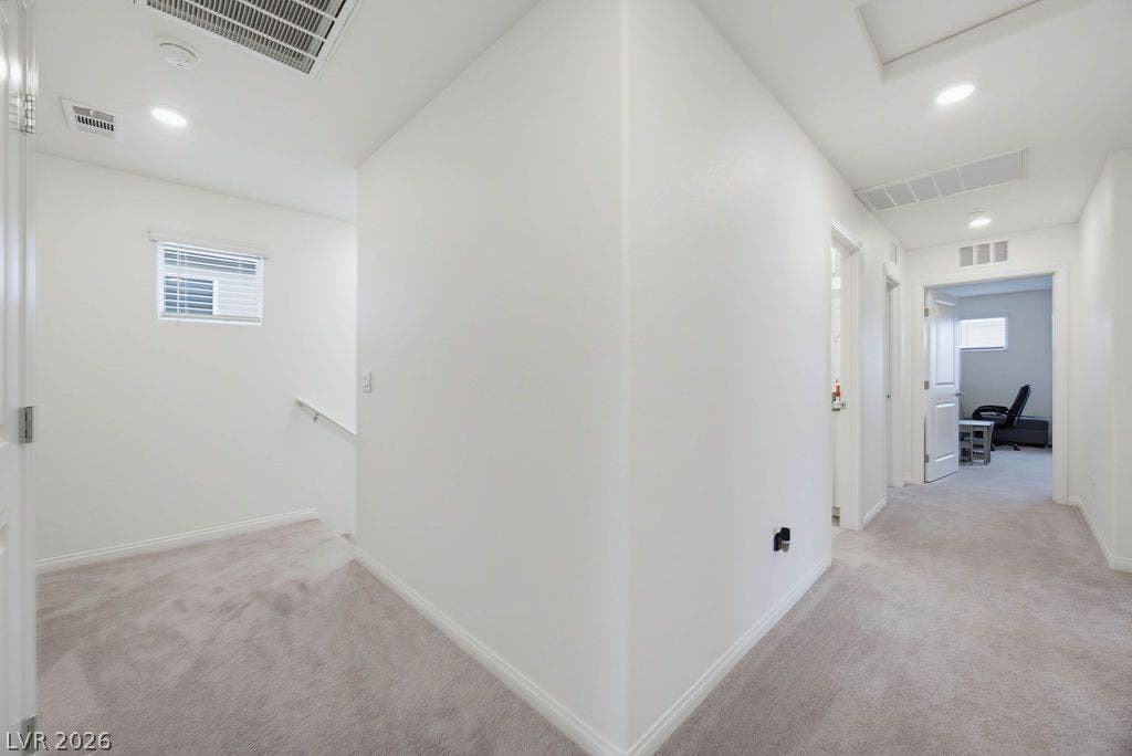 Recessed lighting and soft carpeting elevate this spacious second-floor hallway landing.