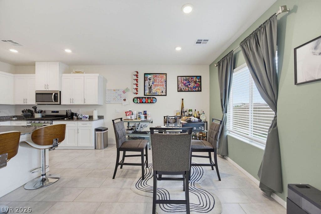 An open dining area flows effortlessly into the kitchen over sleek modern tile flooring.