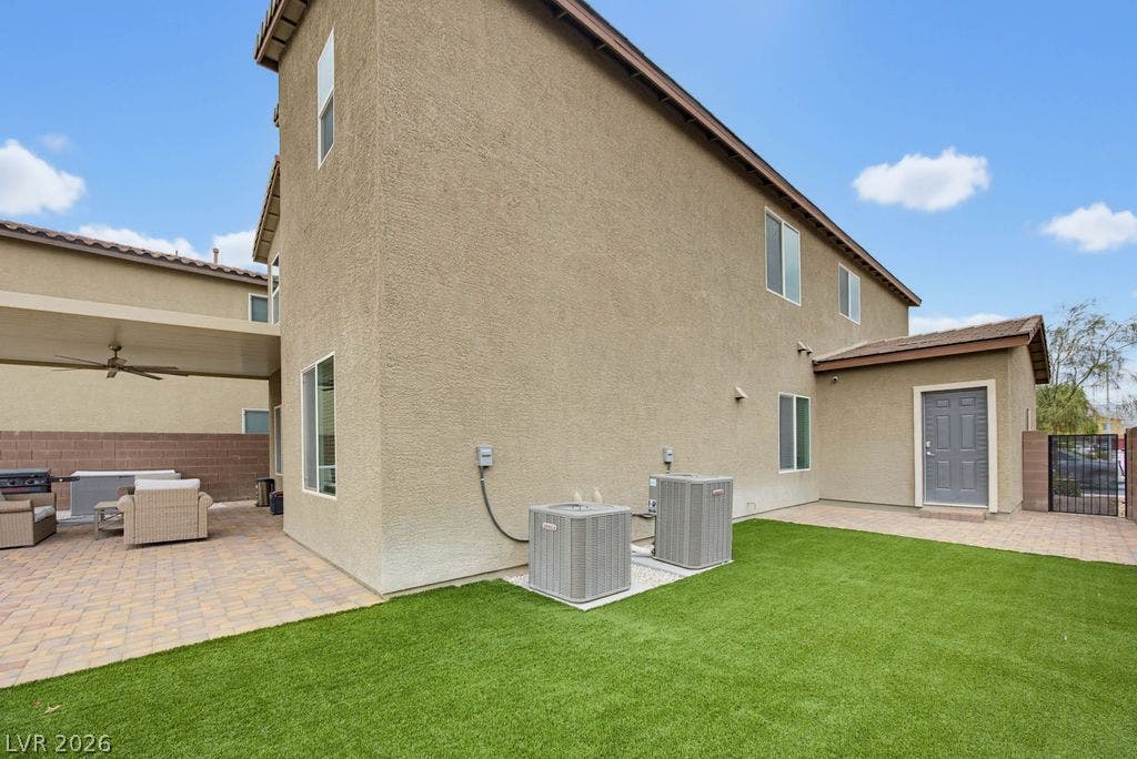 A spacious side yard presents a manicured lawn alongside low-maintenance stone pavers.