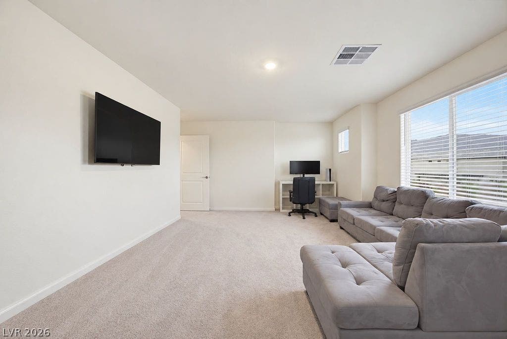 Generous windows fill this carpeted living space with abundant natural light.