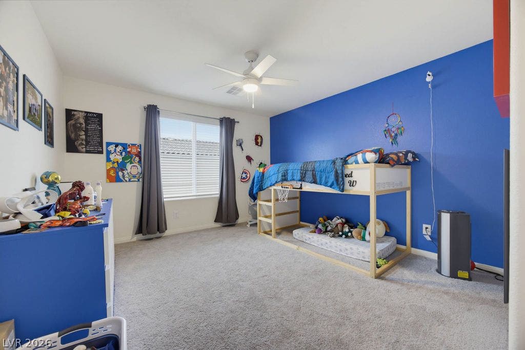 A spacious secondary bedroom features plush carpeting and a large window providing ample natural light.