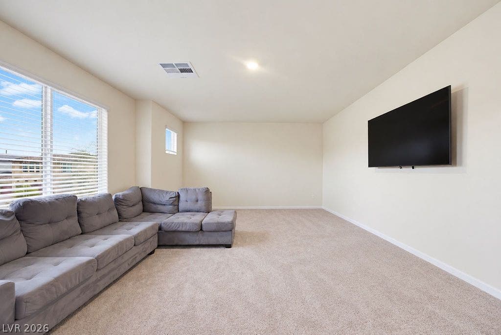 Generous windows fill this carpeted living area with natural light.