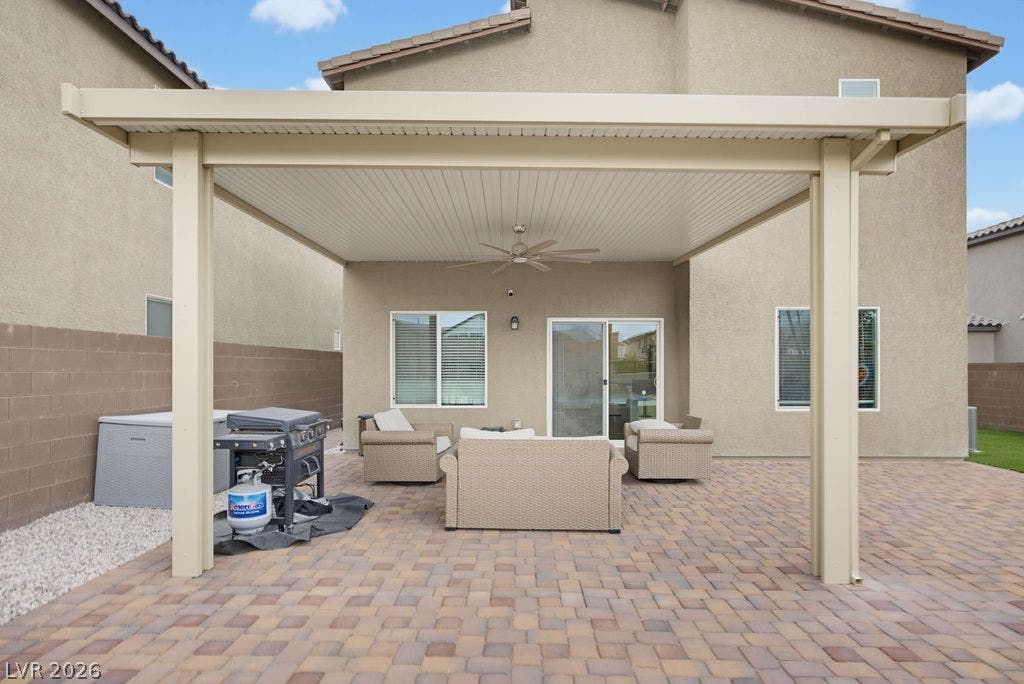 An inviting paved patio sits beneath a protective shade cover attached to the home.