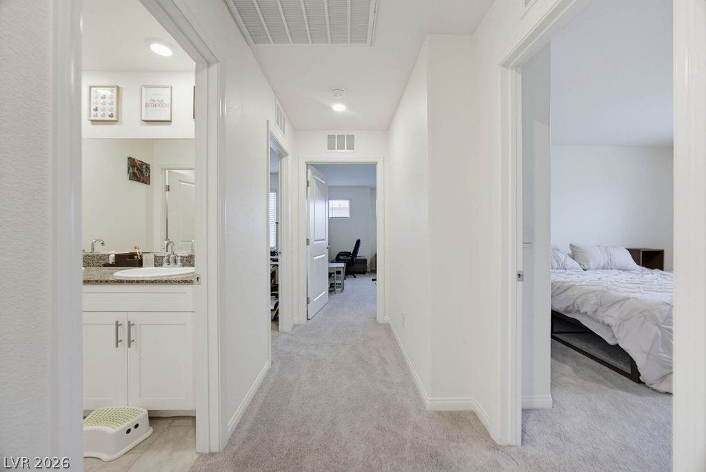 Crisp white walls and soft carpeting define this well-planned hallway connecting bedrooms and baths.