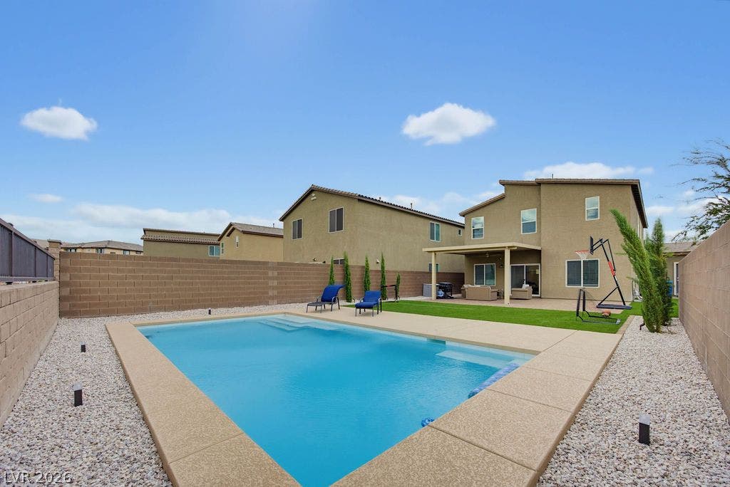 An inviting backyard oasis features a sparkling in-ground pool surrounded by clean concrete decking.