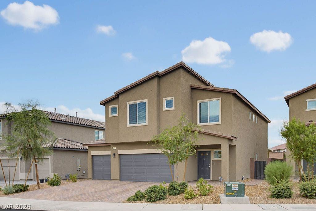 Modern multi-level exterior architecture features a paver driveway leading to an attached garage.