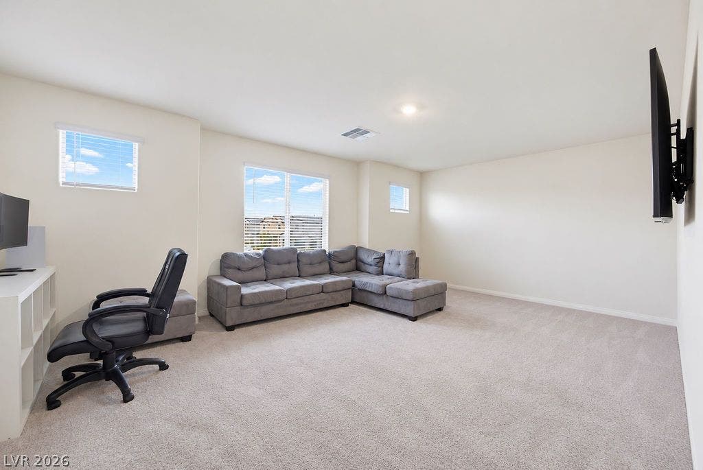 Plentiful natural light fills a versatile upper-level living space featuring soft wall-to-wall carpeting.