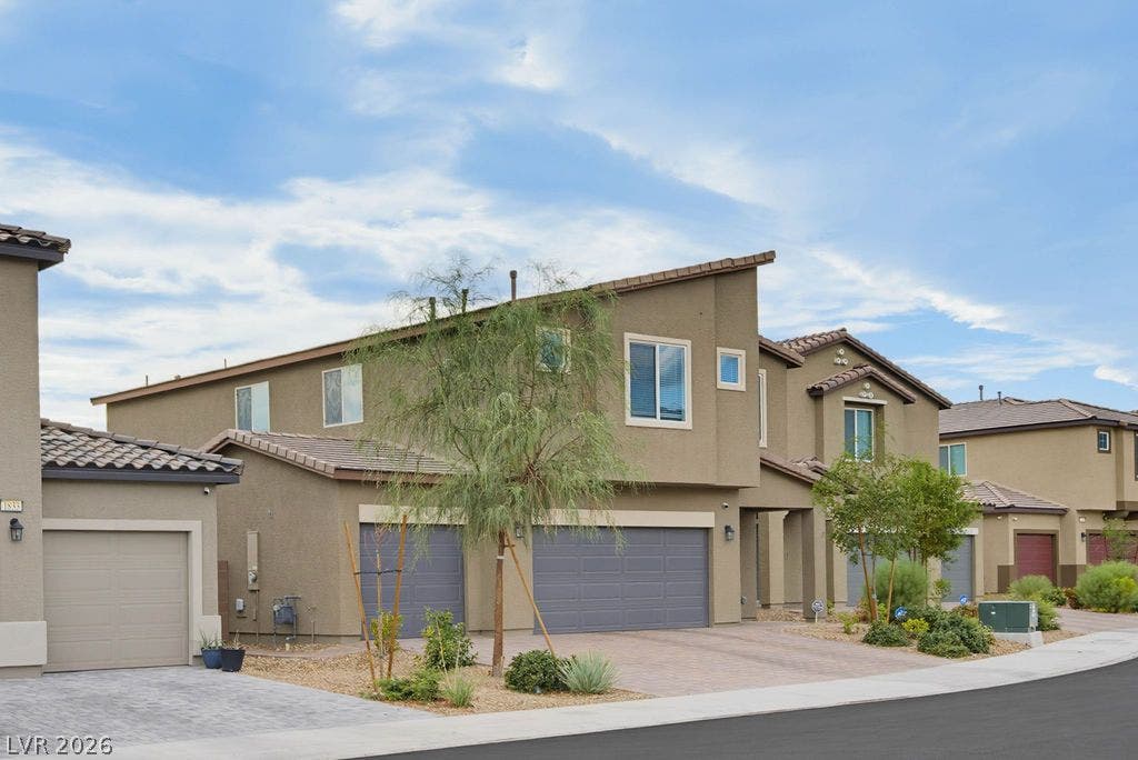 An angular contemporary facade features stucco exterior finishes and a paved driveway.