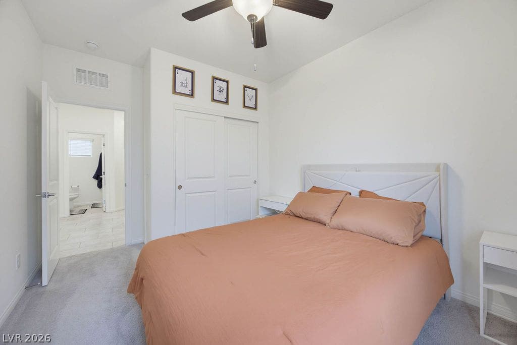 Soft carpeting underfoot defines a serene bedroom connecting directly to a private bathroom.