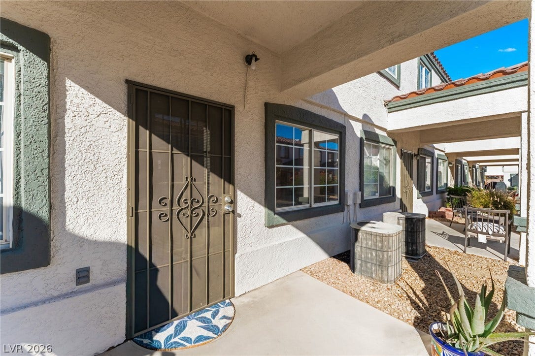 5330 E Charleston Boulevard, #123, Las Vegas, NV 89142 A covered concrete entryway features a stucco exterior wall and a secure metal screen door.