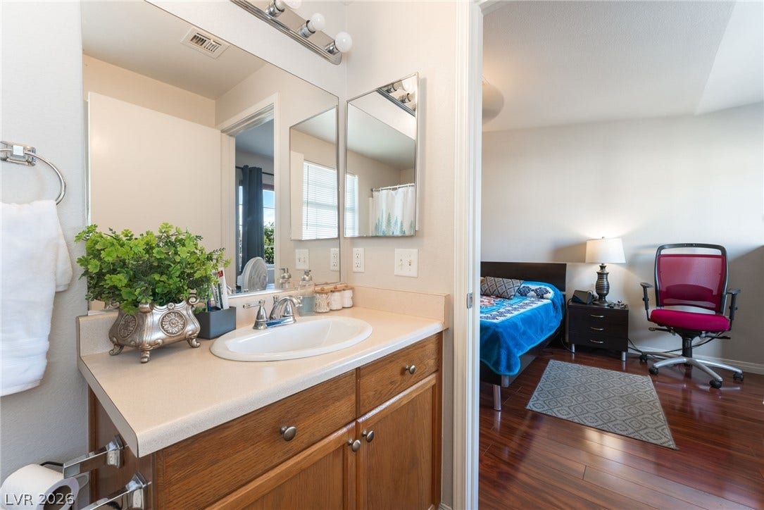 5330 E Charleston Boulevard, #123, Las Vegas, NV 89142 A well-placed vanity overlooks the adjacent bedroom featuring warm wood flooring.