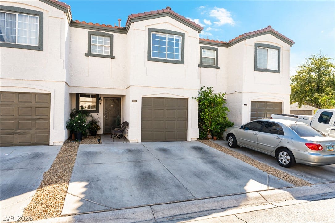 5330 E Charleston Boulevard, #123, Las Vegas, NV 89142 Multi-level townhouse design displays classic stucco walls and concrete driveway parking under blue skies.