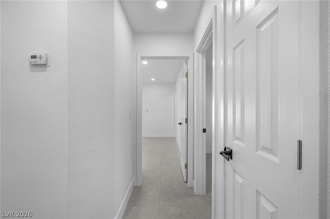Smooth tile floors run through a crisp hallway with recessed overhead lighting.