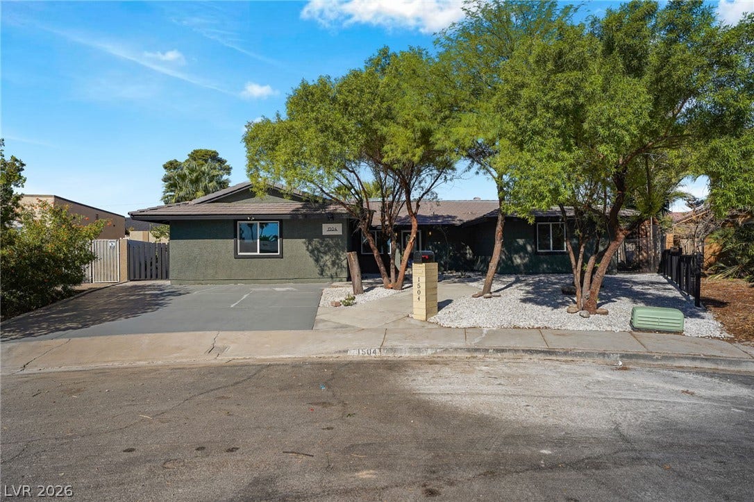 Mature trees frame the exterior of this single-story home with a paved driveway.