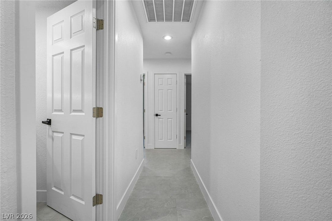Crisp white walls and clean tile flooring define this streamlined hallway layout.
