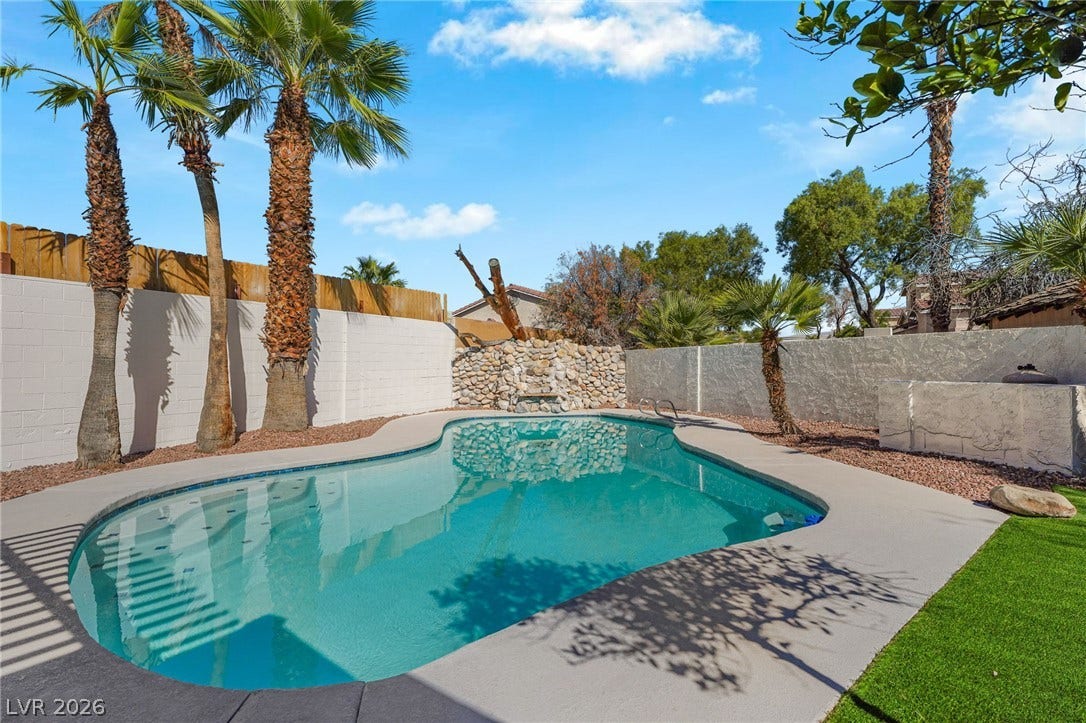 An inviting backyard oasis showcases a sparkling swimming pool framed by towering palm trees.