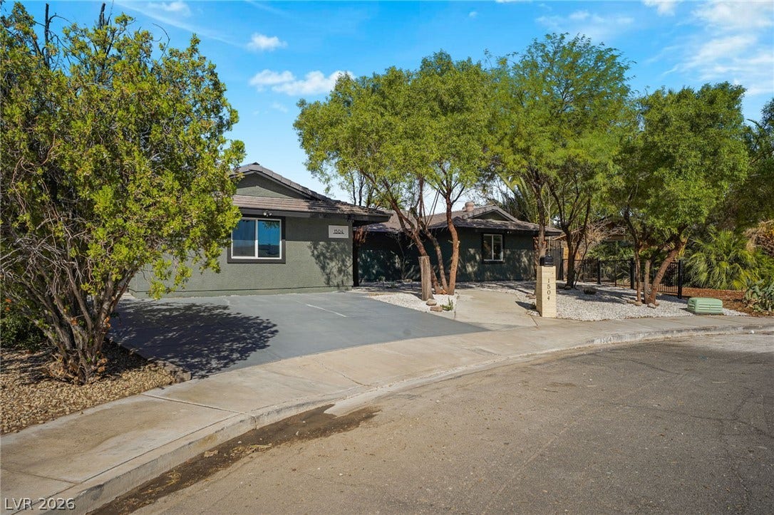 Mature trees shade a quiet street highlighting the exterior of this single-level stucco home.