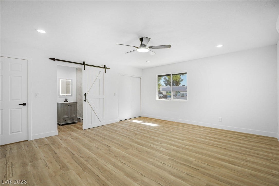 Smooth wood-look flooring and recessed lighting define this spacious bedroom suite with attached bath.