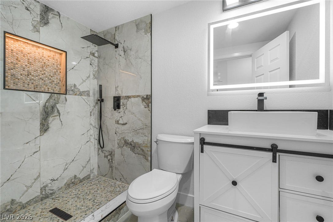 Elegant stone tiling and modern fixtures create a refined, spa-like bathroom atmosphere.