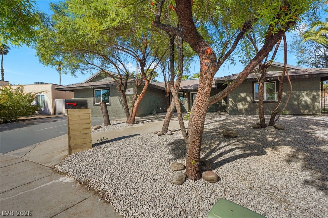 Mature shade trees and low-maintenance desert landscaping frame this welcoming single-level home.