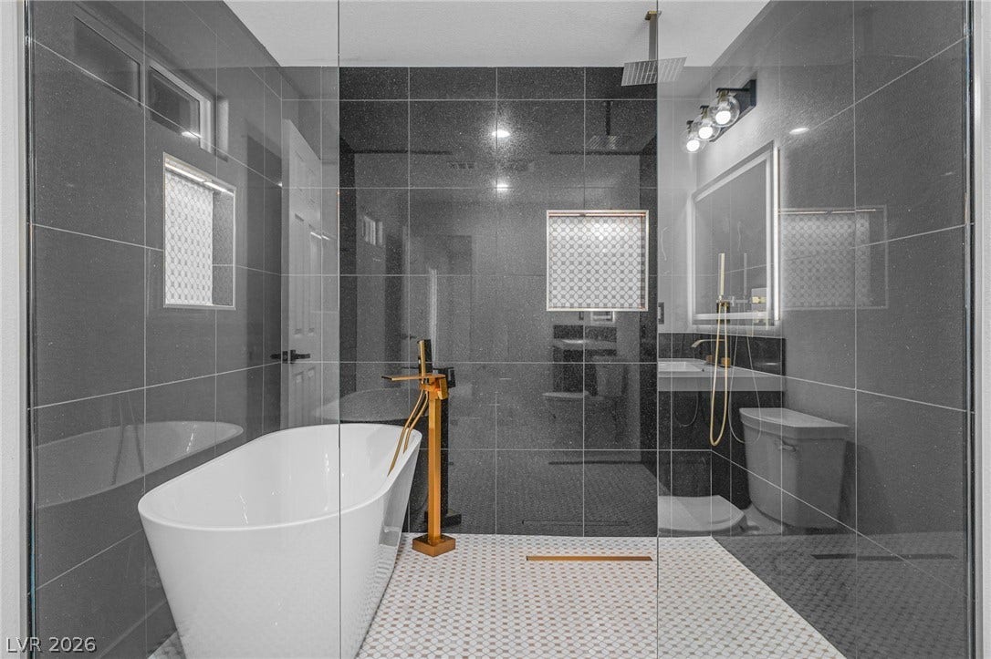 Sleek dark wall tiling and a modern freestanding tub highlight this wet-room design.