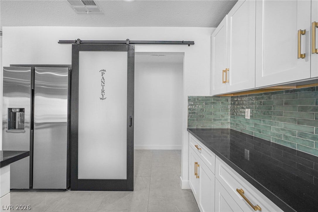 Crisp white cabinetry contrasts beautifully with dark stone countertops and a modern tile backsplash.