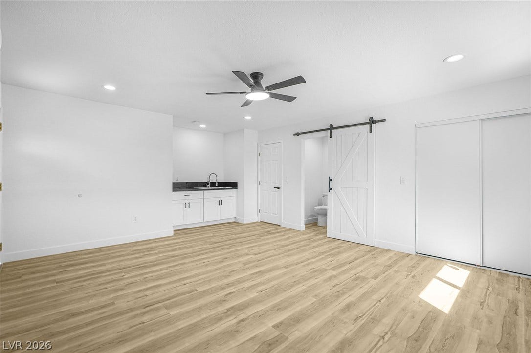 Smooth wood-style flooring runs through this versatile room featuring a convenient wet bar setup.