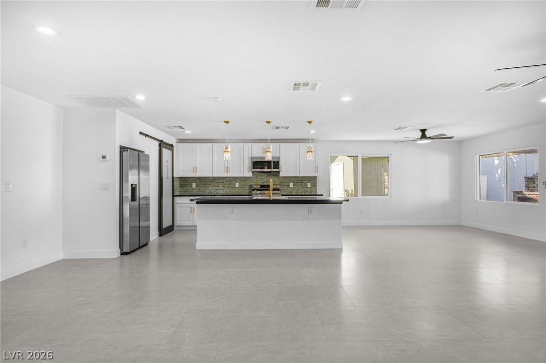 An open layout connects the kitchen to the spacious living area featuring tile floors.