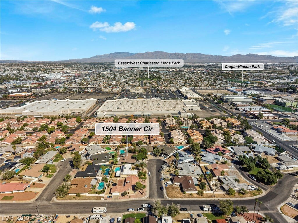An aerial perspective showcases the surrounding neighborhood context and distant mountain backdrops.
