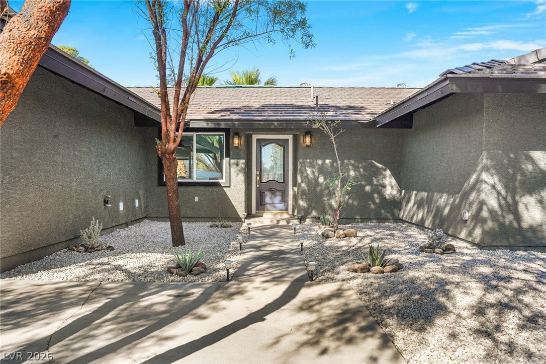 A concrete walkway leads through low-maintenance desert landscaping to a welcoming front entry.