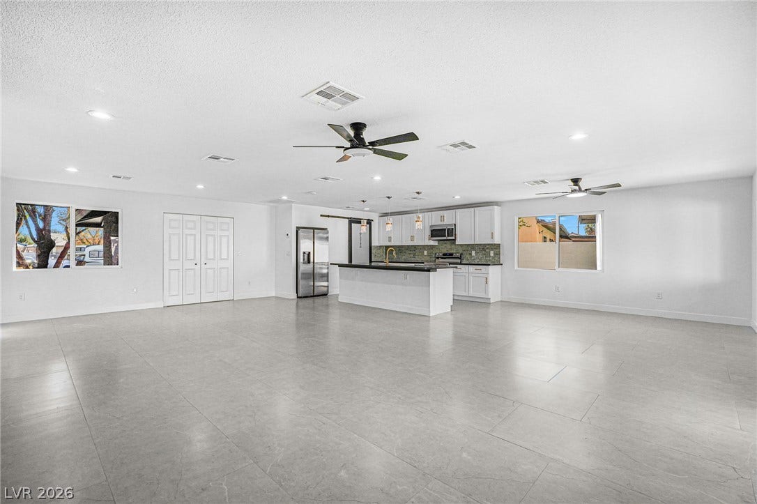 An open layout flows into a modern kitchen with tile flooring and recessed lighting.