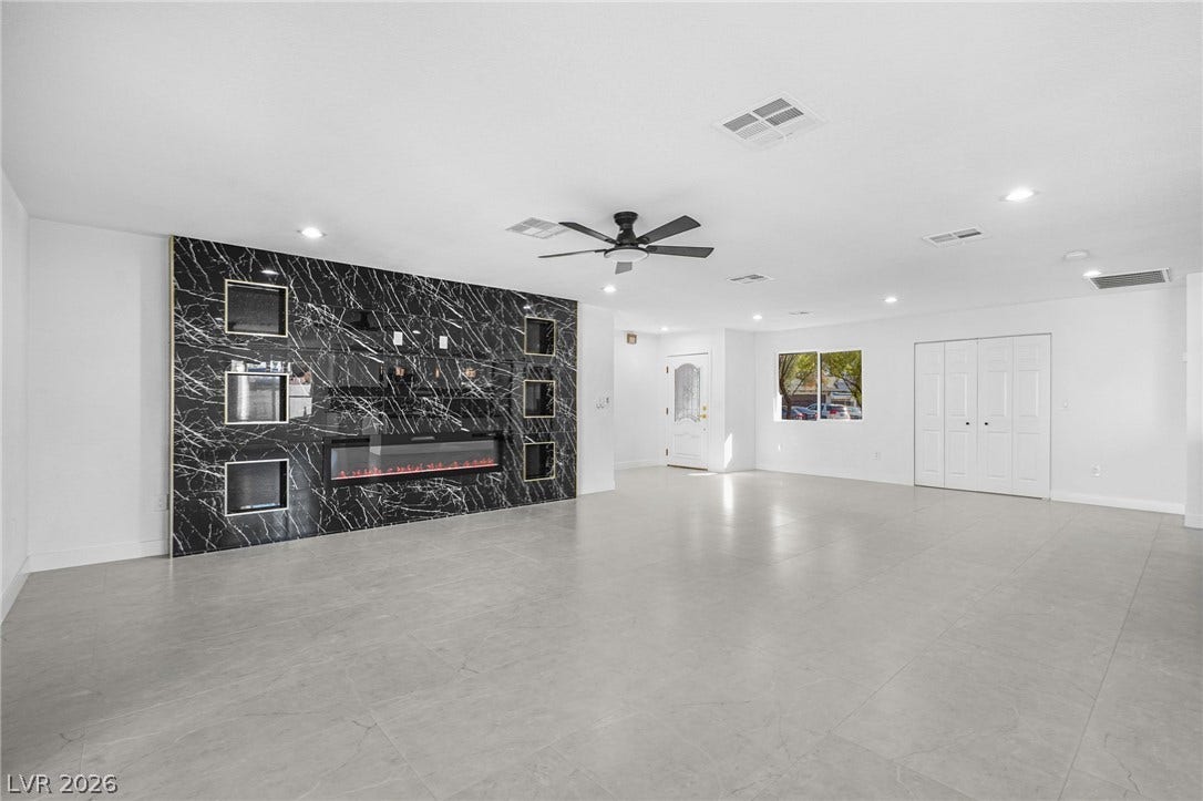 Smooth tile flooring and a massive stone-surround fireplace anchor this open-concept main living space.